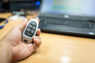 A car digital keyless in the people hand with office working desk as blurred background. Preparing...