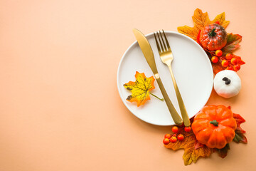 Autumn table setting. White plate, golden cutlery and fall decorations. Flat lay image with copy...