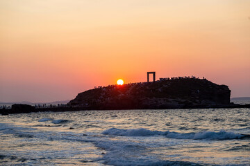 Naxos island, sunset over Temple of Apollo, Cyclades Greece. Visitors admire the sundown background.