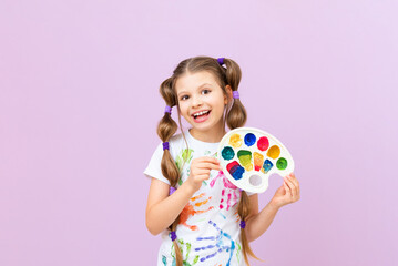 A child with paints on an isolated background, a little girl in a T-shirt with hand prints with paints, a passion for painting.