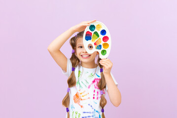A child with paints on an isolated background, a little girl in a T-shirt with hand prints with paints, a passion for painting.