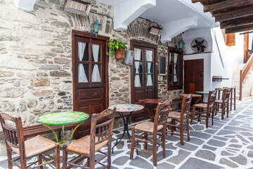 Naxos island, Cyclades Greece. Traditional outdoors cafe wooden ornate chair table on paved street.