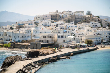 Fototapeta na wymiar Greece, Naxos harbor, Cyclades islands. View from ship of houses, calm sea, blue sky, sunny day.