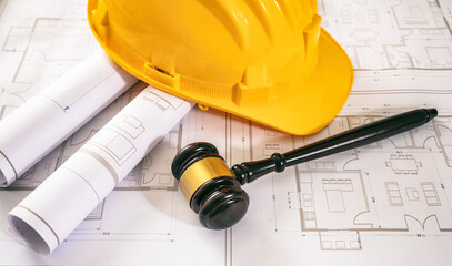 Labor, Construction law. Safety helmet and judge gavel on building blueprint, overhead.