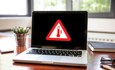 High temperature warning sign on a laptop screen.  Computer overheat, overload, hot weather danger