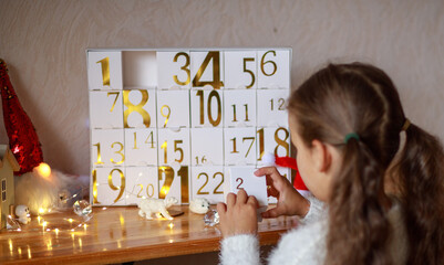 Happy girl opens a box with a gift from the advent calendar, a magic moment, receiving a gift.
