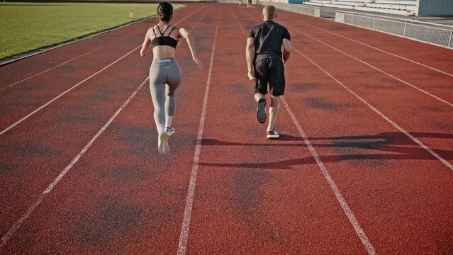 Athletes run low starting on stadium track at summer sunrise