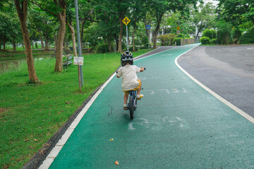 Little asian boy practice ride bicycle in city park