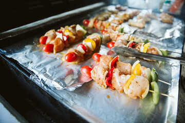 Skewers and Chicken drumsticks are placed on aluminum foil for the grill