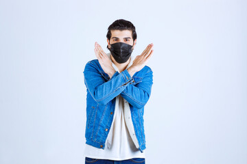 Man in black mask giving stop sign to the virus