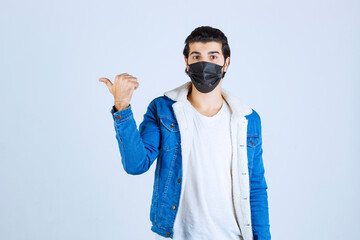 Naklejka premium Man wearing black mask and pointing to the left