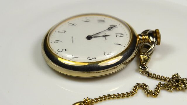 pocket watch with five minutes to twelve on a turn table