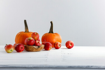 Pumpkin and apples on a white table in a bright room in the fall season, free space.