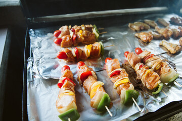 Skewers and Chicken drumsticks be places on aluminium foil for grill