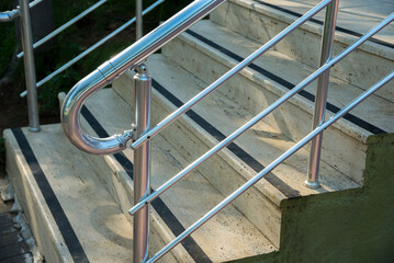 Concrete stairs with stainless handrails. Anti slip tape on stairs
