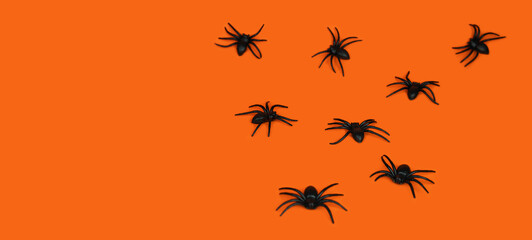 Festive background for Halloween. Black spiders on an orange background. Banner. Copy space. Selective focus.