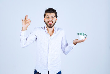 Fototapeta premium Man in a white shirt holding a coffee mug and enjoying it
