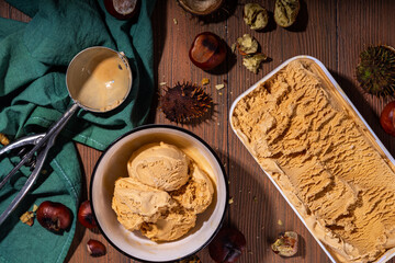 Autumn spicy ice cream with the roasted chestnut taste, with spices, on a wooden background with fresh and roasted chestnuts
