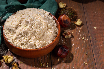 Chestnut flour, unusual vegan gluten-free flour, on wooden background with fresh and roasted chestnuts