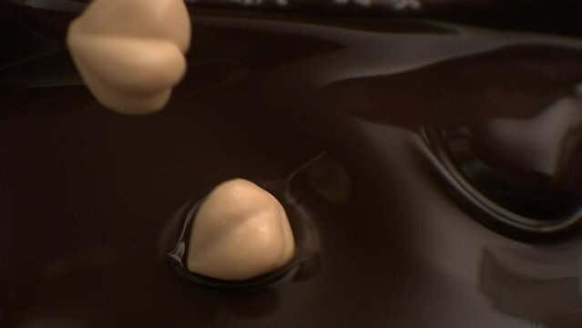 hazelnut falling to melted chocolate, mixing hazelnut with chocolate 