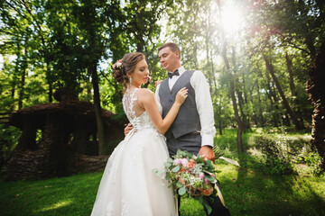 Happy smile bride and groom look at each other and running in the green garden. Wedding in the summer in the park.