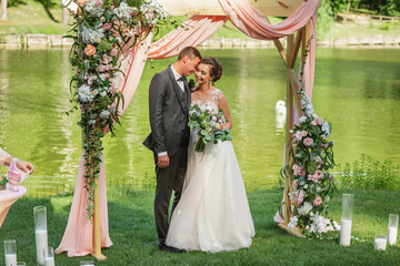 beautiful bride and groom in the wedding ceremony area of live white and pink flowers.