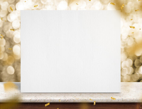 Blank White Paper Poster On Marble Table With Gold Sparkling Confetti At Gold Bokeh Lights At Background
