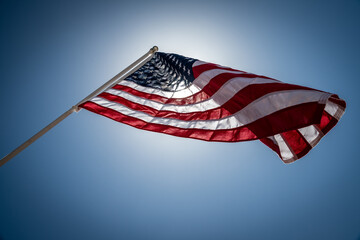 American flag in front of sun on a clear day