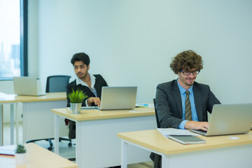 Two business working in the office with computer laptop on table.