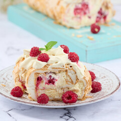 Baked meringue roll with cream and fresh red raspberry, white background.