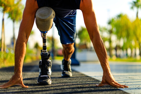 disabled athlete man with prosthetic leg starting to run at the beach on a treadmill outdoors at sunset