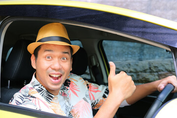 Asian man looking at camera and give thumb up from inside his car