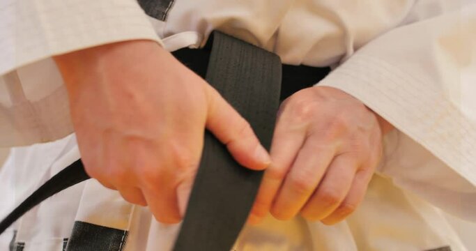 homme qui noue sa ceinture noir judo