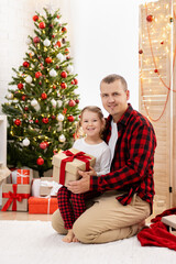 Obraz na płótnie Canvas Happy father and daughter sitting near Christmas tree