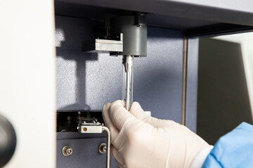 Scientist loading a test tube containing a patient sample on the  flow cytometer for analysis. Flow...