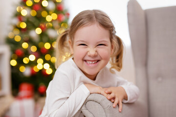 Close up portrait of a funny little girl near christmas tree