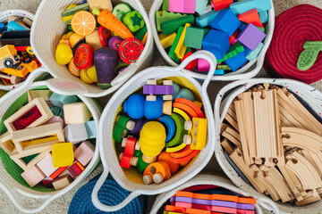 Colorful Toy Storage Baskets in the children's room. Cloth stylish Baskets with wooden toys. Organizing and Storage Ideas in nursery. Clean up toys and reduce the clutter. Top view - obrazy, fototapety, plakaty