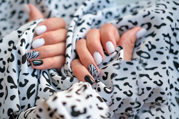 Beautiful female hands with manicure on the background of leopard fabric. Stylish nail design....