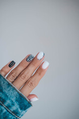 Beautiful female hands with a manicure in a denim jacket. Stylish nail design. Manicure with black and white zebra stripes on the nails. © smile35