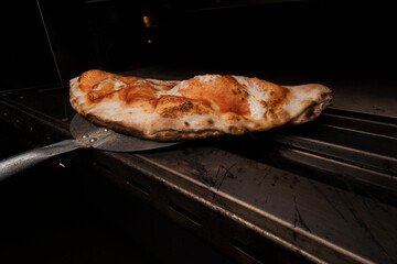 Pizza clazone saliendo del horno, lista para que los clientes coman comida hecha al estilo italiano...