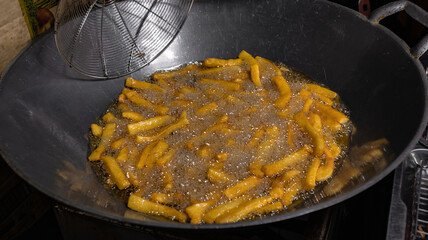 Close up French fries with hot oil in the dirty wok at street food market stall