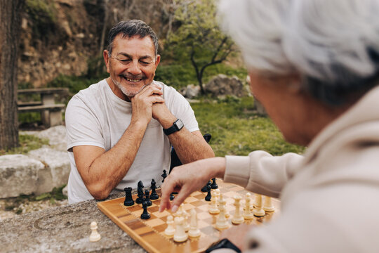 Mature couple enjoying a game of chess in a park