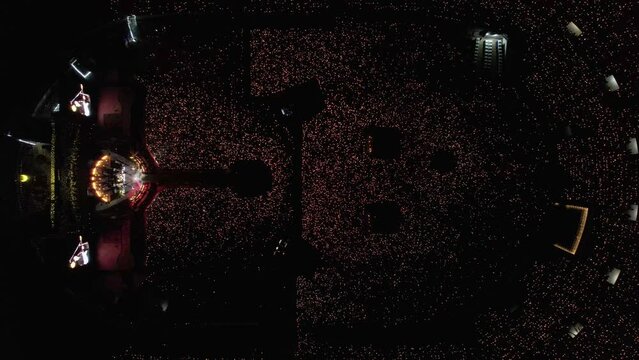 Aerial top down view of a concert in a large stadium with a light show emitted by thousands of fans.