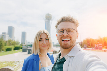 Happy caucasian lover couple traveler takes selfie photo against Baiterek of NurSultan Astana...