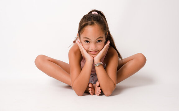 Full length photo of young attractive little girl sit floor stretching training gym isolated over white color background