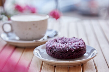 Natural no sugar doughnut and cappuccino on wooden table. Aesthetic coffee time outside.