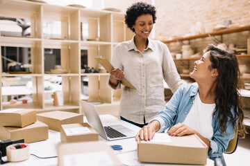 Cheerful female entrepreneurs smiling at each other in a warehouse