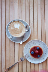 Blueberry and raspberry berry tart on the white ceramic plate with cup of cappuccino. Aesthetic breakfast. Top view food