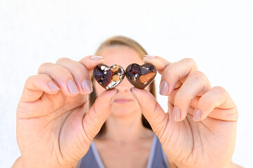 Two heart-shaped chocolates in the hands of a young 35 year old woman. Selective focus