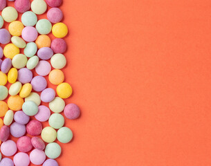 Obraz premium Frame of colorful candies over orange background with copy space